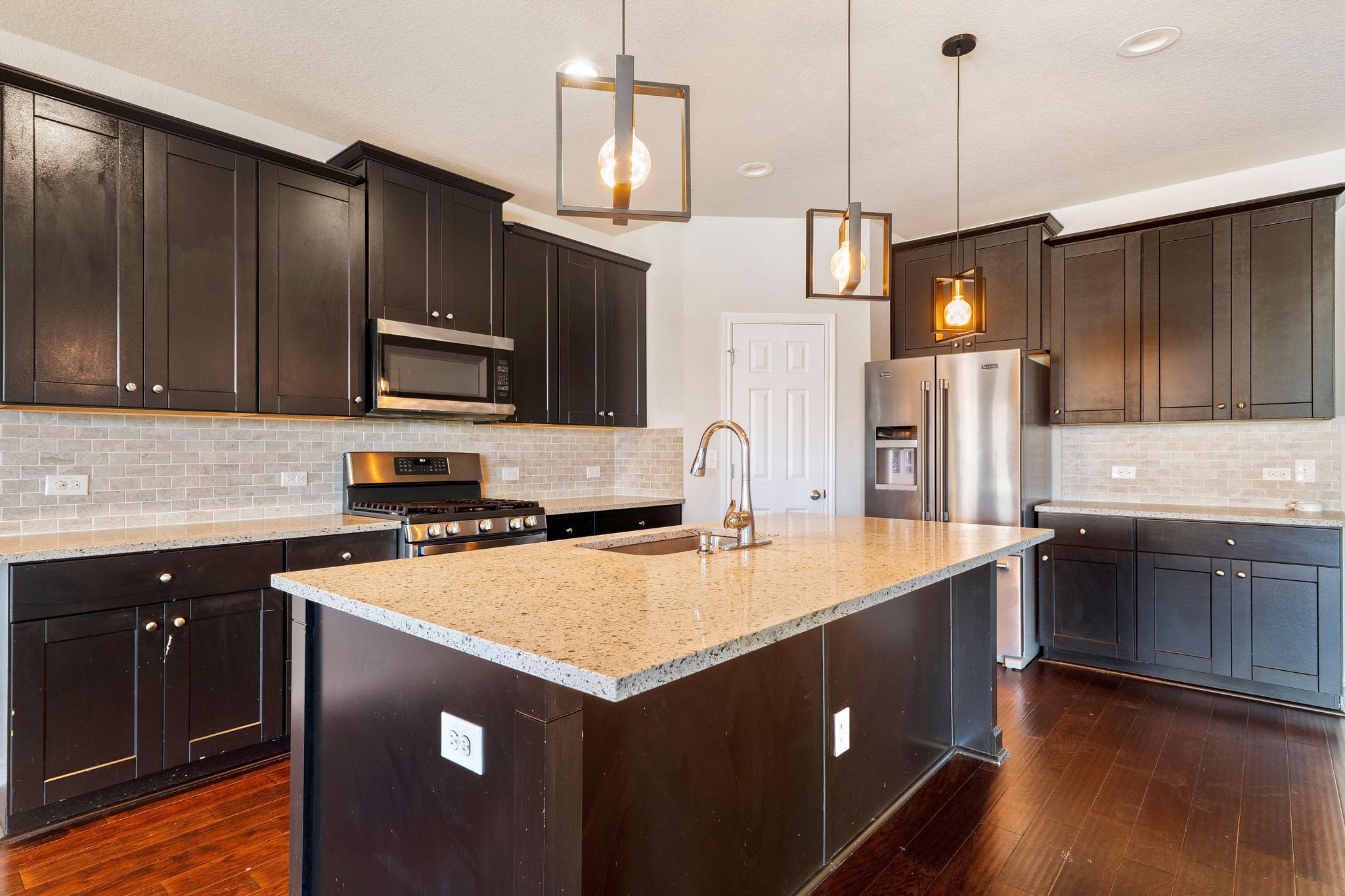 1341 Eagle Ray Street Leander, TX 78641 - Photo 6 of 37 A contemporary kitchen features rich cabinetry, lustrous granite counters, and stainless-steel appliances.