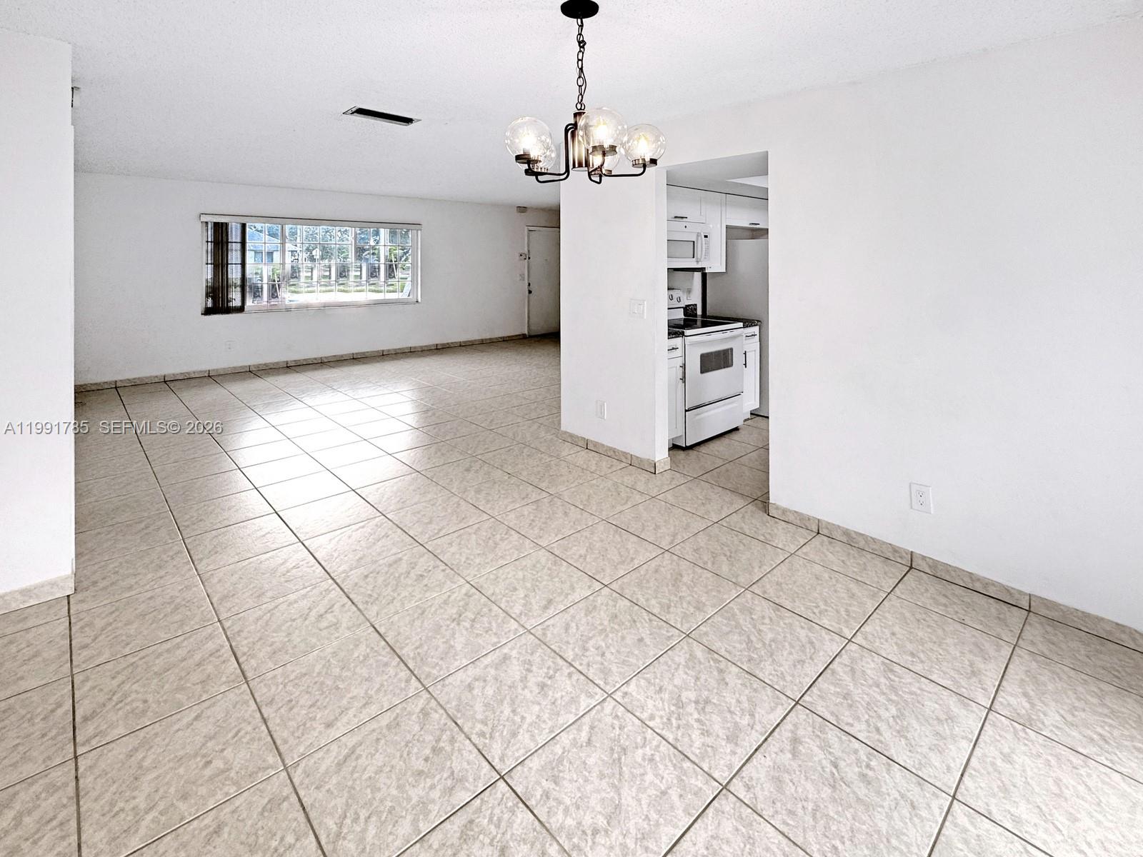 6802 Southwest 34th Court Miramar, FL 33023 - Photo 12 of 41 a view of a livingroom with wooden floor a chandelier and windows
