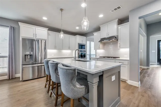 a kitchen with kitchen island granite countertop stainless steel appliances a sink counter space and a refrigerator