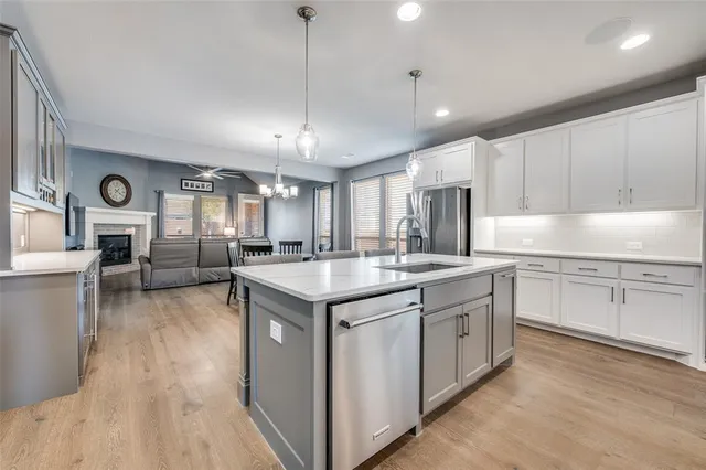 a kitchen with stainless steel appliances granite countertop a sink a stove and a wooden floors