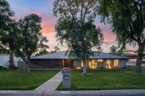 a front view of a house with a garden and a tree