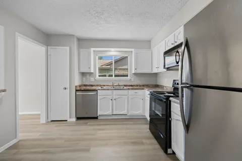 a kitchen with stainless steel appliances granite countertop a refrigerator sink and stove