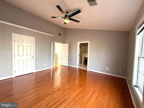 a view of empty room with wooden floor and fan