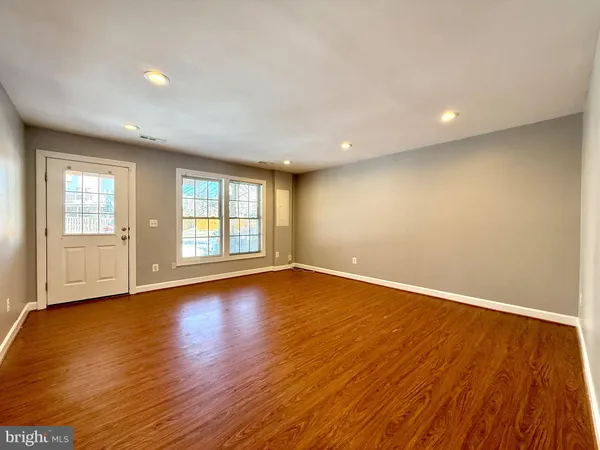 a view of an empty room with wooden floor and window