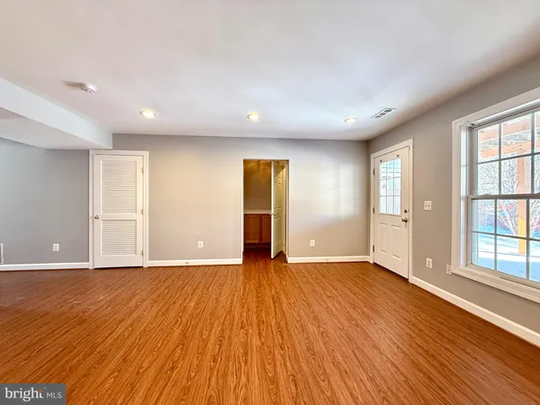 a view of an empty room with wooden floor and windows
