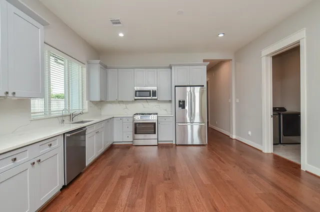 a kitchen with wooden floors white cabinets and stainless steel appliances