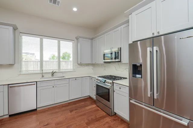 a kitchen with stainless steel appliances white cabinets and a refrigerator