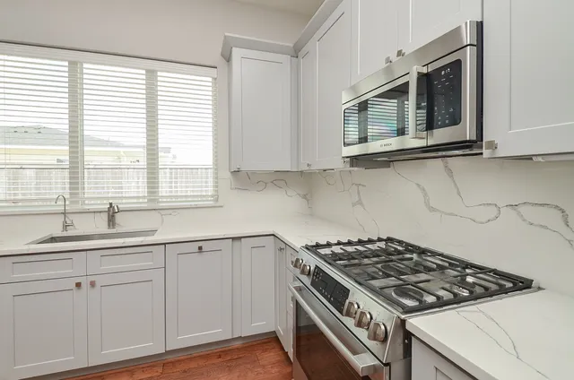 a kitchen with granite countertop a sink stove and cabinets