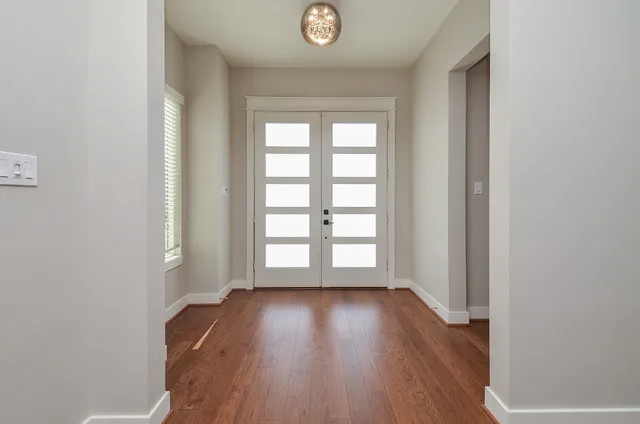an empty room with wooden floor and windows