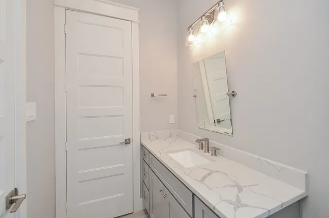 a bathroom with a granite countertop sink and a mirror