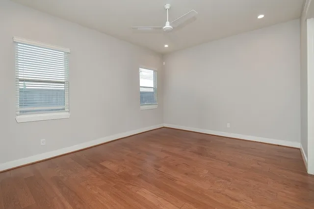 an empty room with wooden floor and windows