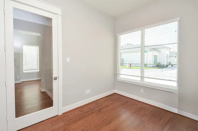 an empty room with wooden floor and windows