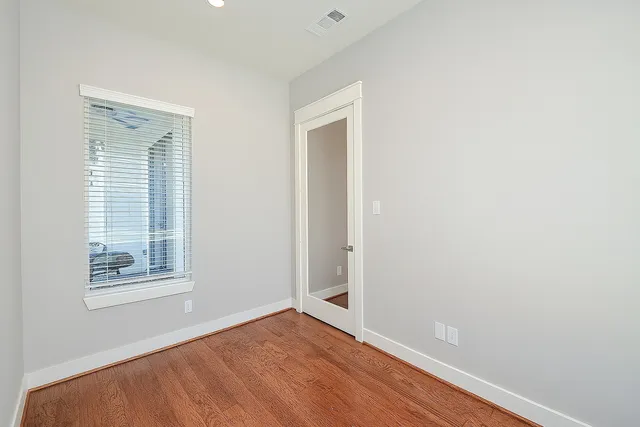 a view of an empty room with wooden floor and a window
