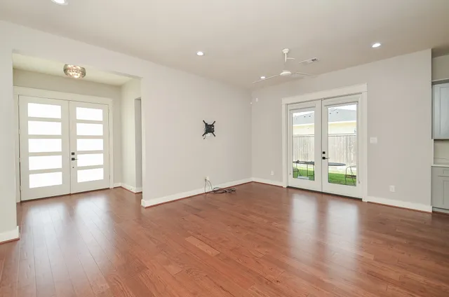 an empty room with wooden floor and windows
