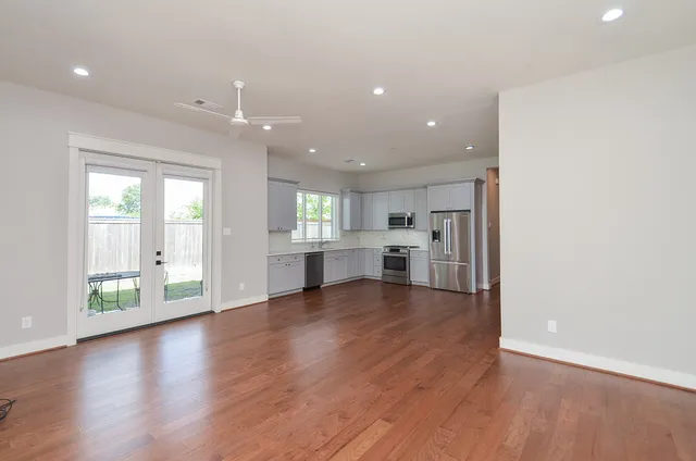 a view of an empty room with kitchen and window