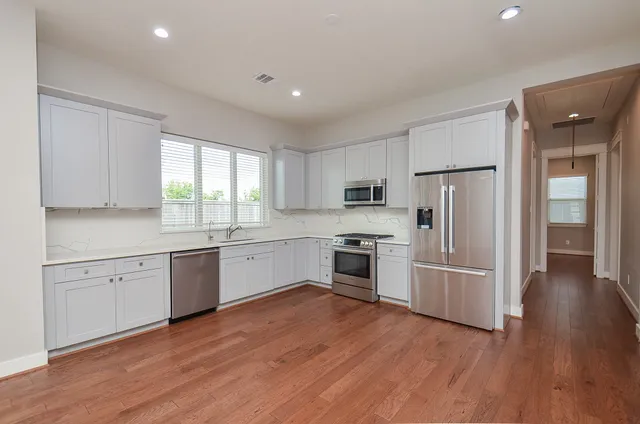 a kitchen with granite countertop white cabinets and stainless steel appliances