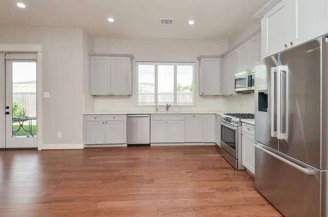 a kitchen with white cabinets stainless steel appliances and a window