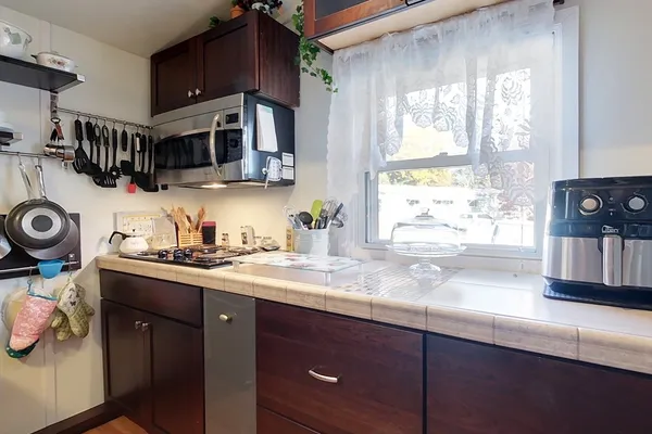 a kitchen with stainless steel appliances granite countertop a sink a stove and a wooden cabinets