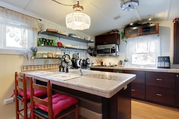 a kitchen with stainless steel appliances granite countertop a sink dishwasher and a refrigerator with wooden floor