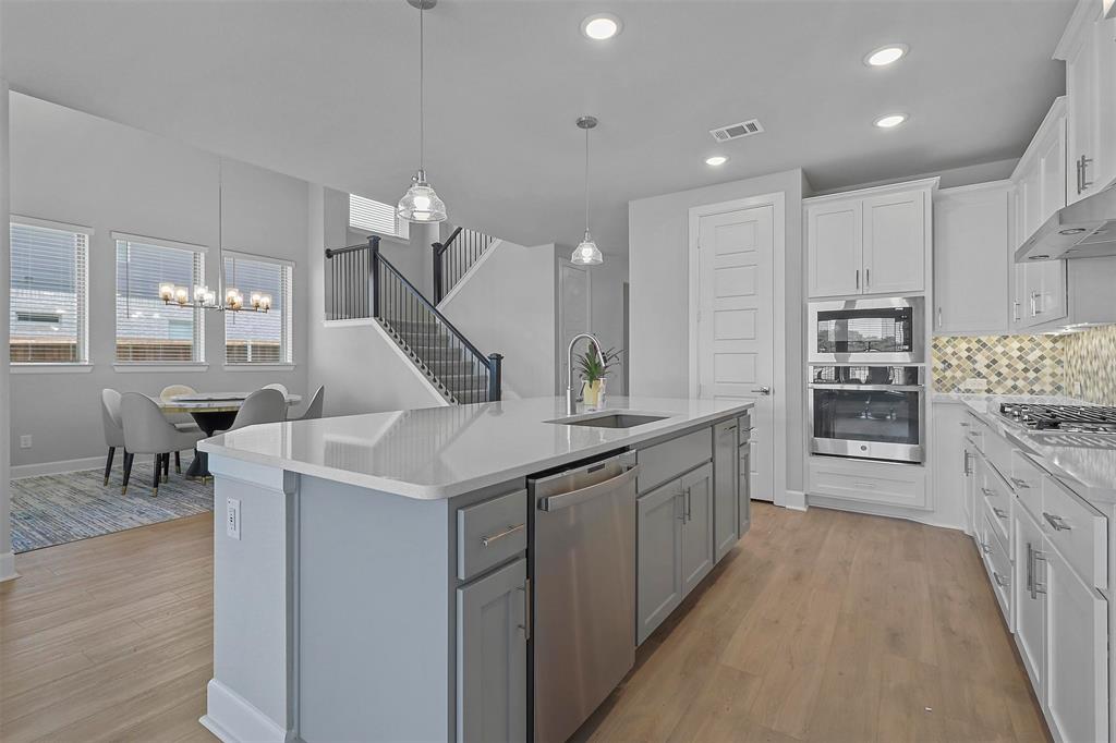a large kitchen with stainless steel appliances kitchen island granite countertop a lot of cabinets and wooden floor