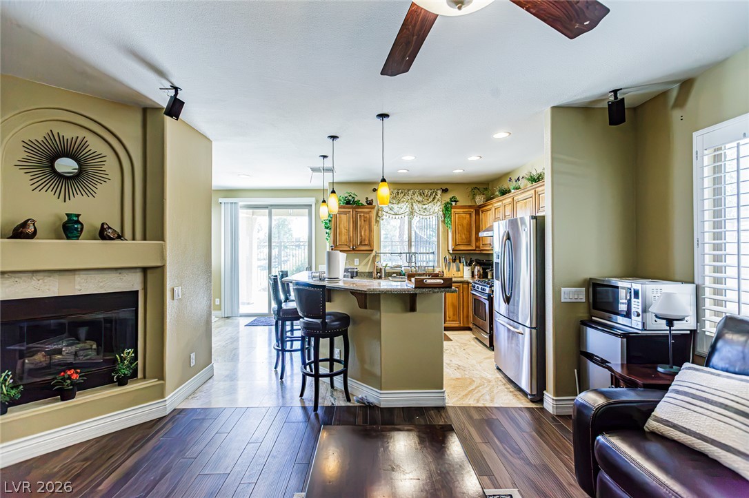 75 Tall Ruff Drive Las Vegas, NV 89148 - Photo 17 of 64 Hardwood floors and an inviting fireplace transition seamlessly into a modern kitchen space.