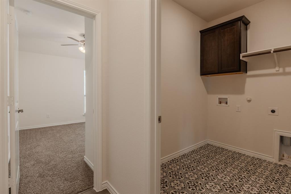 2902 Trusting Way Aubrey, TX 76227 - Photo 22 of 38 Laundry area with patterned floor tile, dark wood-finish wall cabinetry, and an upper storage shelf