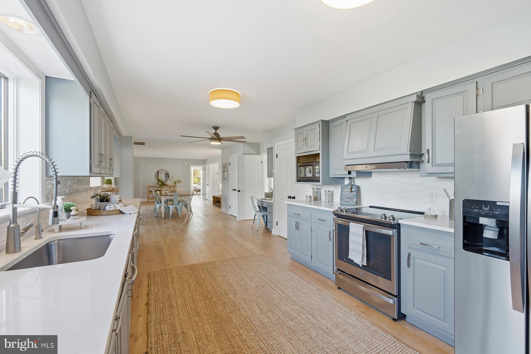 25500 Chance Farm Road St. Michaels, MD 21663 - Photo 14 of 43 a kitchen with stainless steel appliances a stove a sink a refrigerator white cabinets and wooden floor