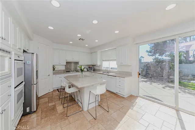 a kitchen with stainless steel appliances granite countertop a sink a stove a dining table and chairs