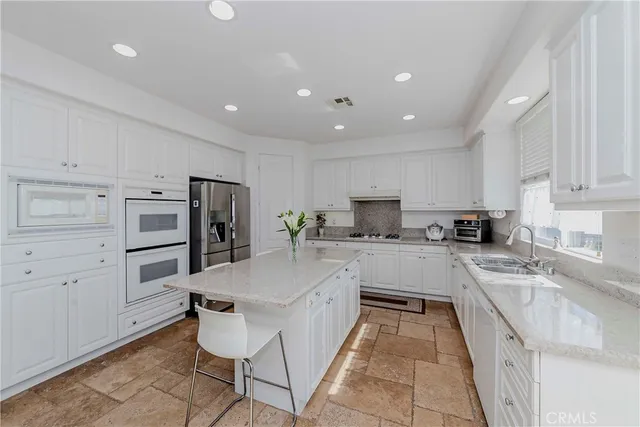 a kitchen with stainless steel appliances granite countertop a refrigerator and a stove top oven