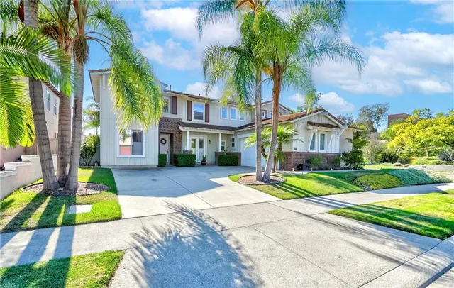 a view of a white house with a small yard plants and palm trees