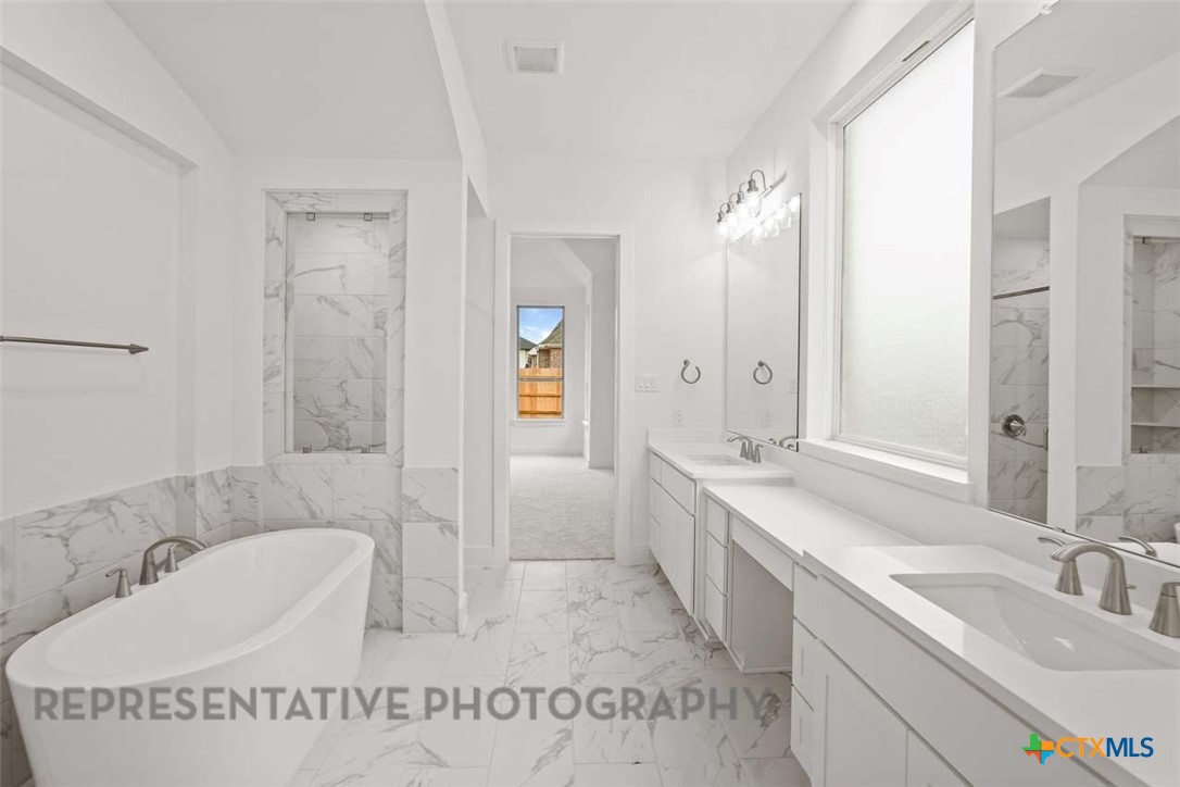 129 Ribera Drive Liberty Hill, TX 78642 - Photo 11 of 23 a spacious bathroom with a tub sink and mirror