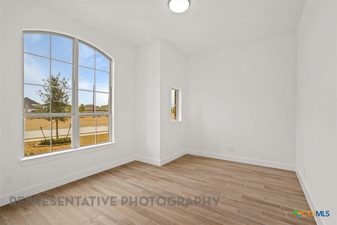 129 Ribera Drive Liberty Hill, TX 78642 - Photo 12 of 23 a view of an empty room with wooden floor and a window