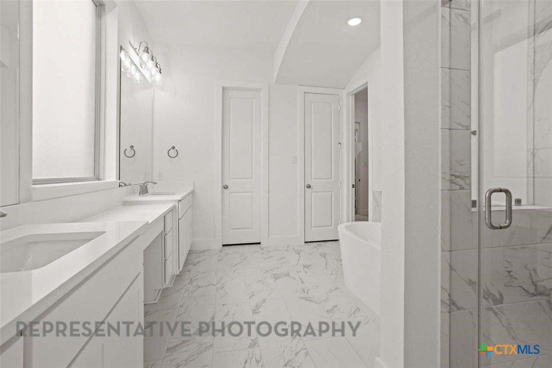 129 Ribera Drive Liberty Hill, TX 78642 - Photo 9 of 23 a spacious bathroom with a granite countertop sink a mirror and shower