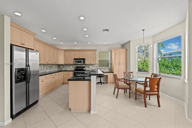 a view of a kitchen with kitchen island a large window cabinets and stainless steel appliances