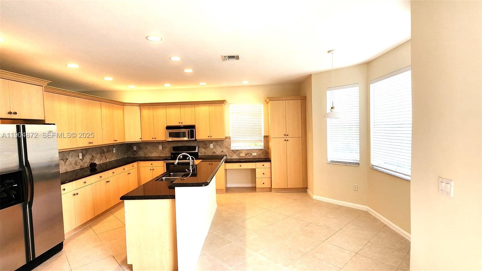 9042 Dupont Place Wellington, FL 33414 - Photo 8 of 43 a large kitchen with kitchen island a large counter top space a sink stainless steel appliances and cabinets