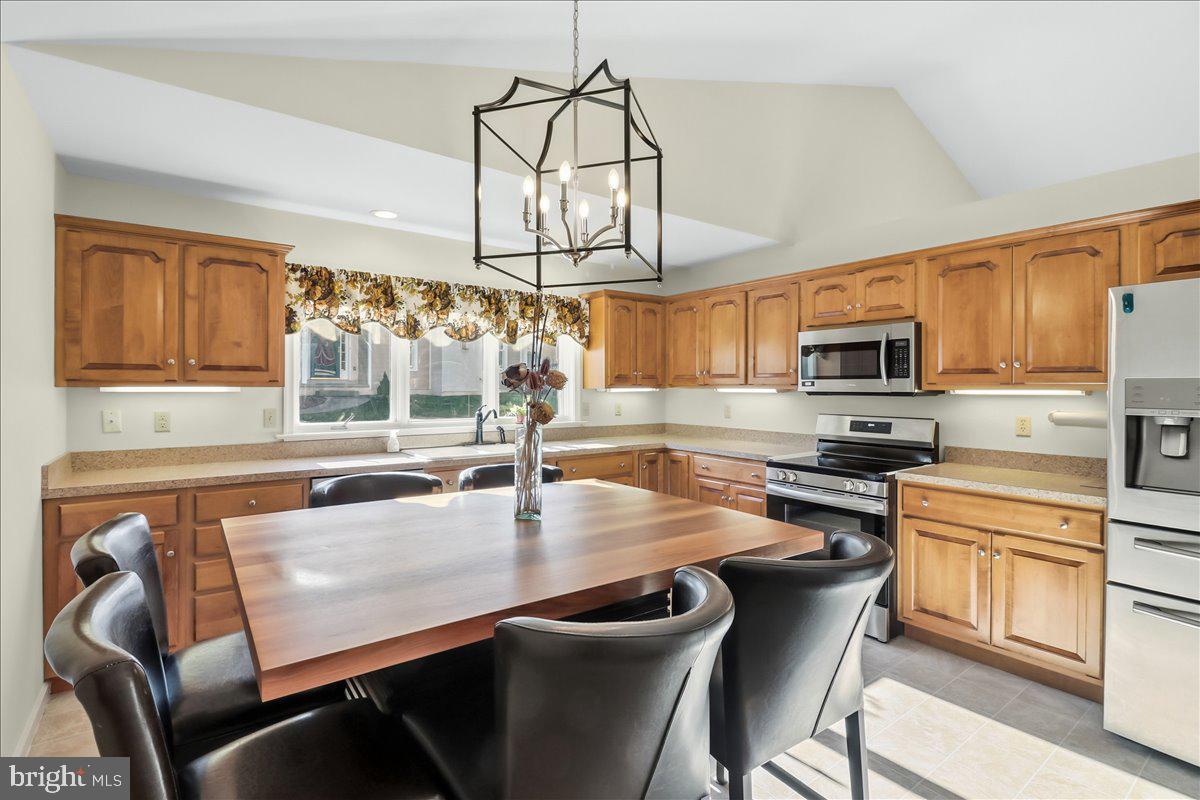 9 Parkside Drive Elverson, PA 19520 - Photo 4 of 33 a kitchen with stainless steel appliances granite countertop a sink dishwasher a stove a refrigerator with a dining table and chairs with wooden floor