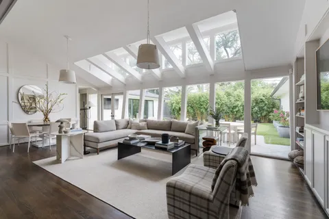 a living room with furniture large window and wooden floor