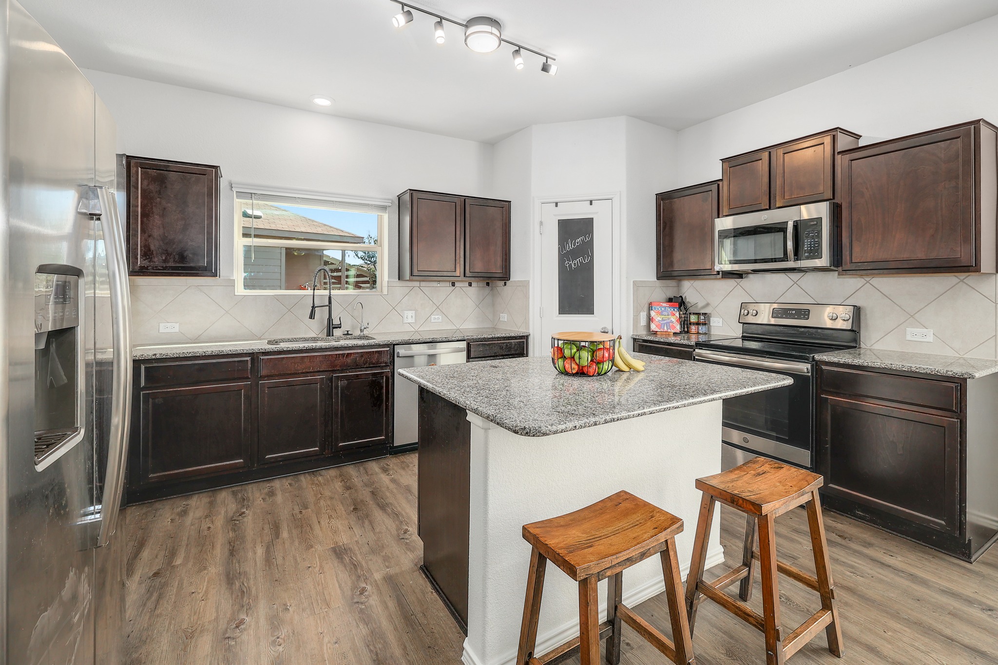 735 Circle Way Jarrell, TX 76537 - Photo 7 of 32 Rich wood cabinetry and a central island ground this functional kitchen workspace.