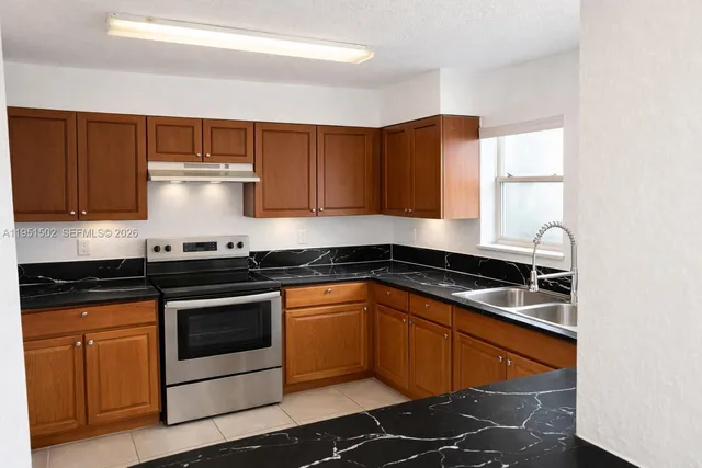 a kitchen with granite countertop wooden cabinets and a stove top oven