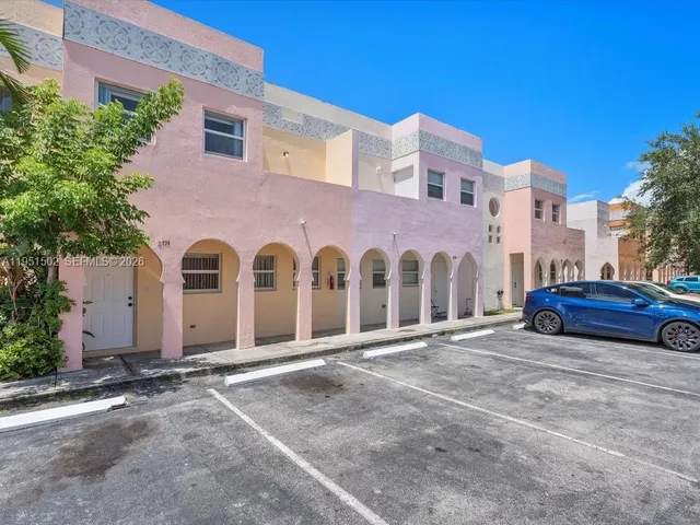 a view of a blue house with large windows and a car parked in front of it