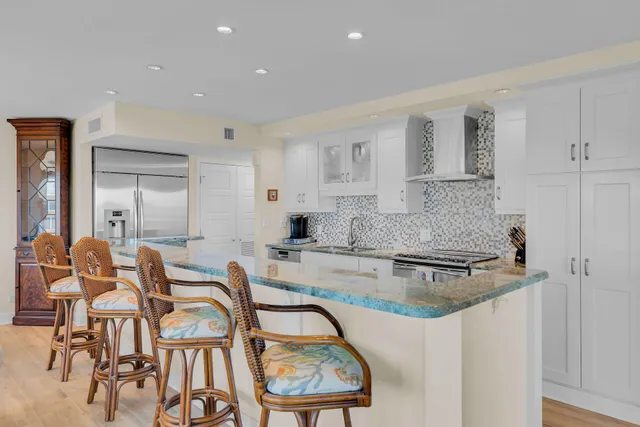 a kitchen with white cabinets and chairs