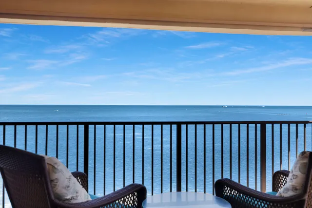 a view of a swimming pool with a lawn chairs under an umbrella next to a road