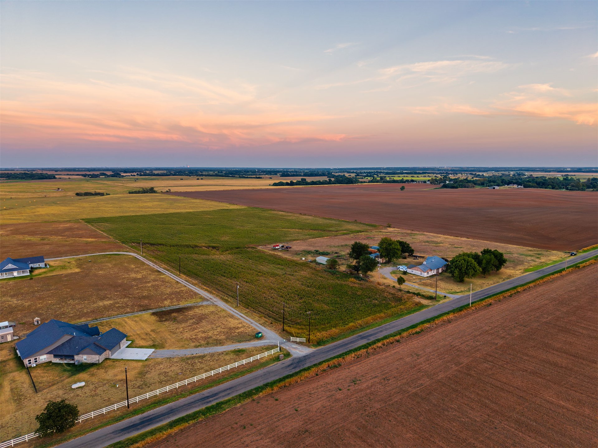 16 North Gregory Road Yukon, OK 73099 - Photo 15 of 34 Expansive rural setting featuring agricultural fields, a paved road, and scattered residential properties with distinct rooflines