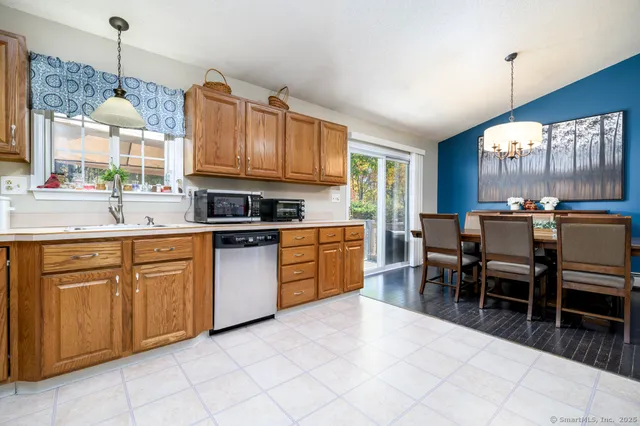 a kitchen with stainless steel appliances granite countertop a stove top oven a sink dishwasher a dining table and chairs with wooden floor