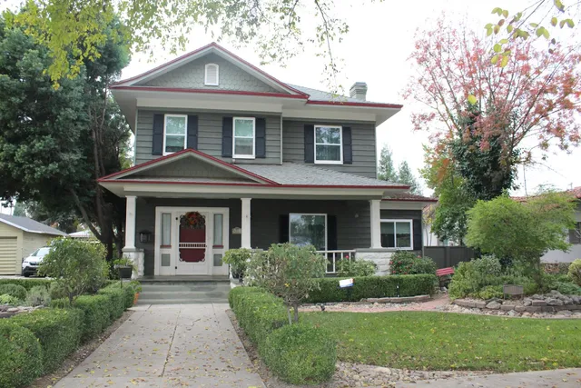 a front view of a house with a yard and trees