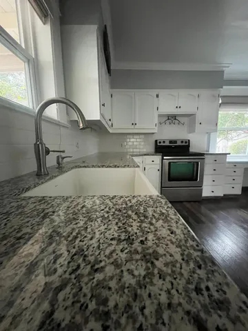 a kitchen with kitchen island granite countertop a sink stove and refrigerator