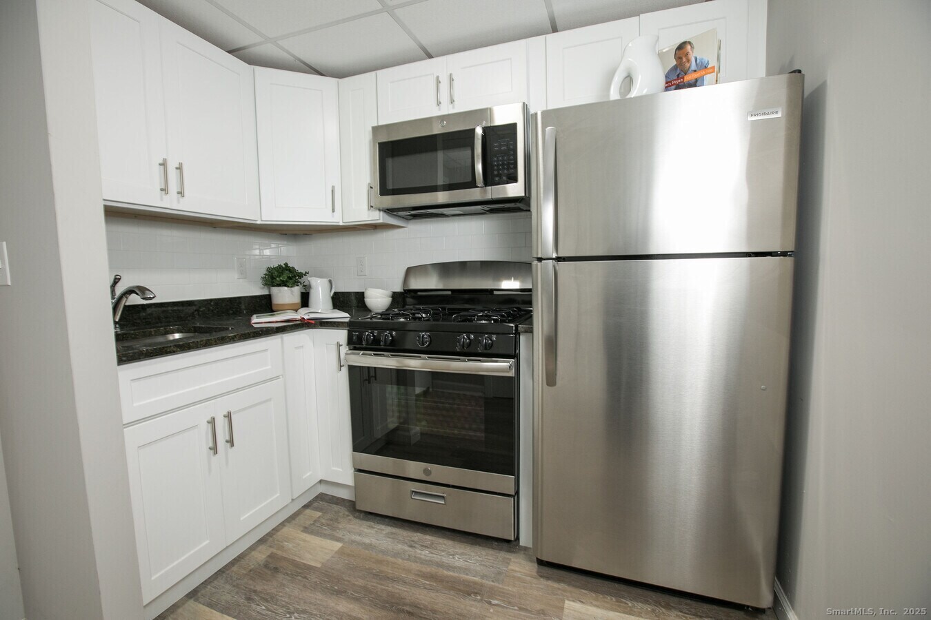 225 Lordship Boulevard, Unit 1F Stratford, CT 06615 - Photo 4 of 19 a kitchen with cabinets stainless steel appliances and wooden floor