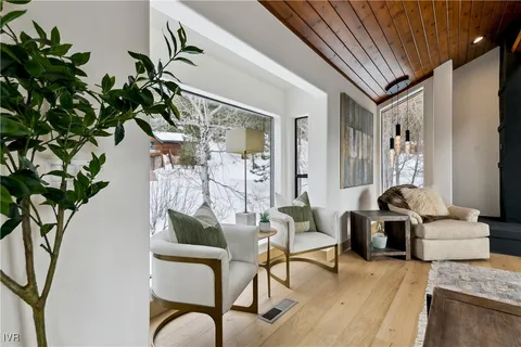 a living room with furniture a large window and wooden floor