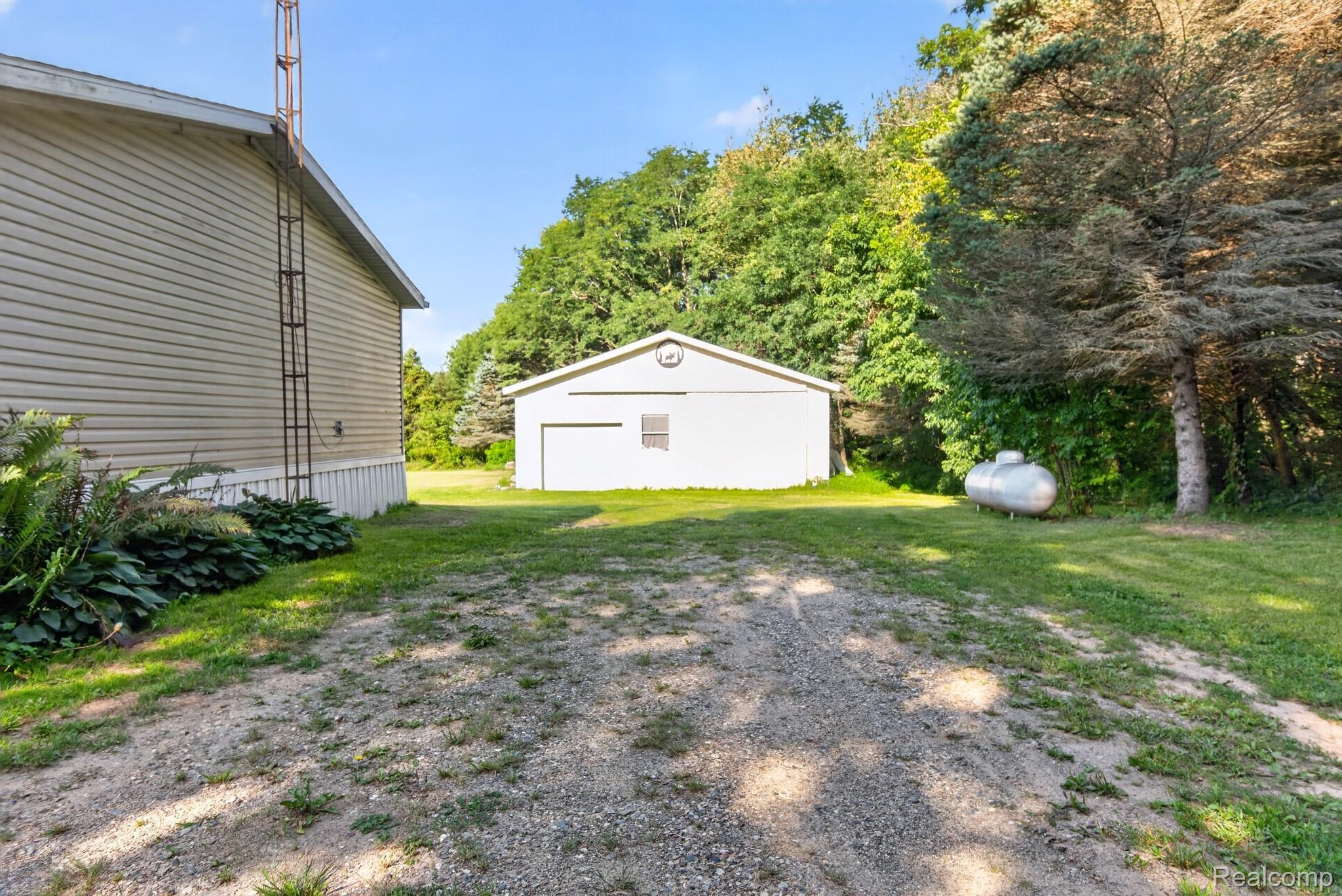 6266 Kikendall Road Eaton Rapids, MI 48827 - Photo 10 of 36 Detached garage with a single bay door, gravel driveway, and mature landscaping