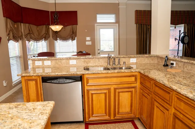 a kitchen with stainless steel appliances granite countertop a sink and wooden cabinets
